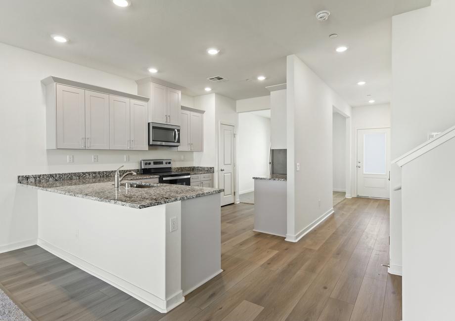 The kitchen has stainless steel appliances and plank flooring.