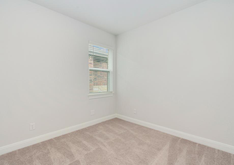 Secondary bedroom with a single window and tan carpet.