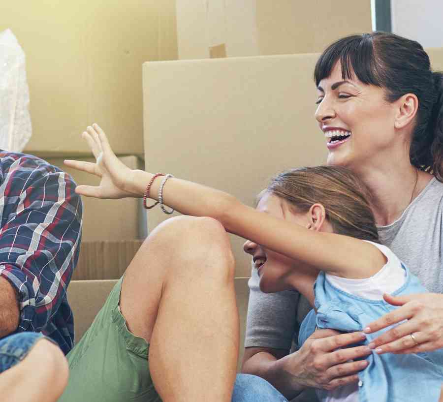 Family sitting on the floor surrounded by moving boxes.