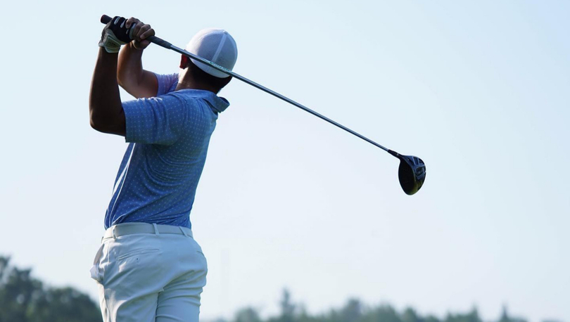 Golfer with club following through on golf swing.