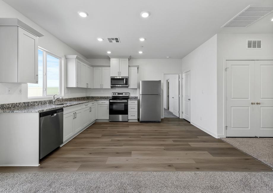 The kitchen has stainless steel appliances and plank flooring.