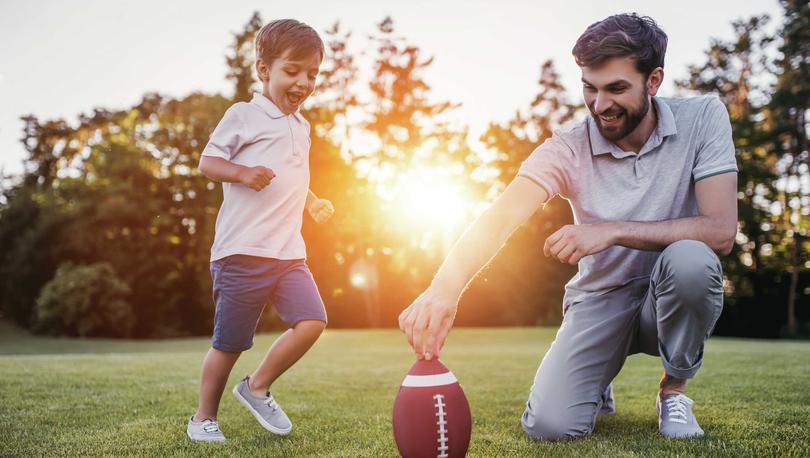 Father and son playing football in field.