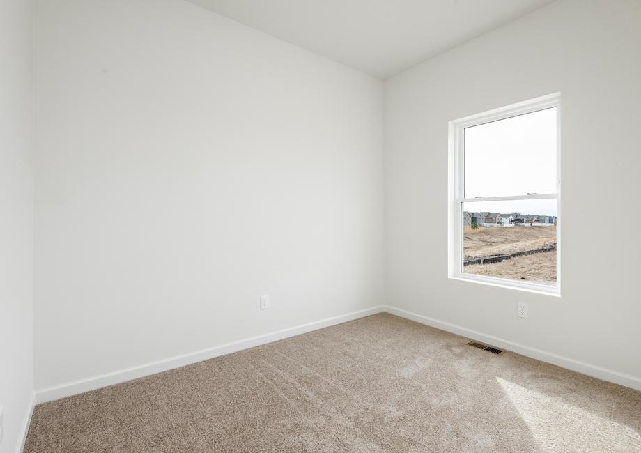 The secondary bedroom has carpet and a window.