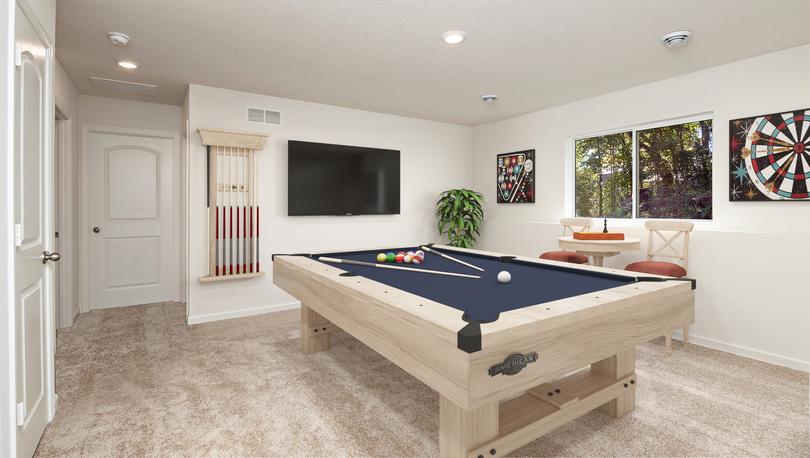 Furnished game room with a pool table on lower level of a split-level home with a lookout window view of the back yard and forest.