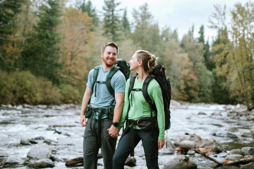 Photo of a young couple backpacking along a river in Washington state in fall.