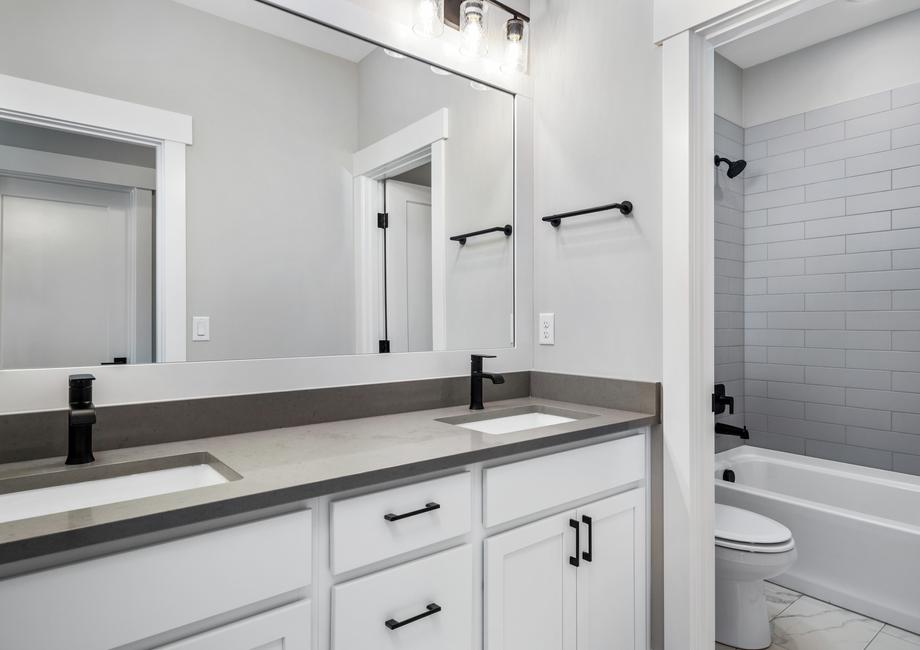 The secondary bathroom includes a large vanity with beautiful cabinetry and matte black hardware.