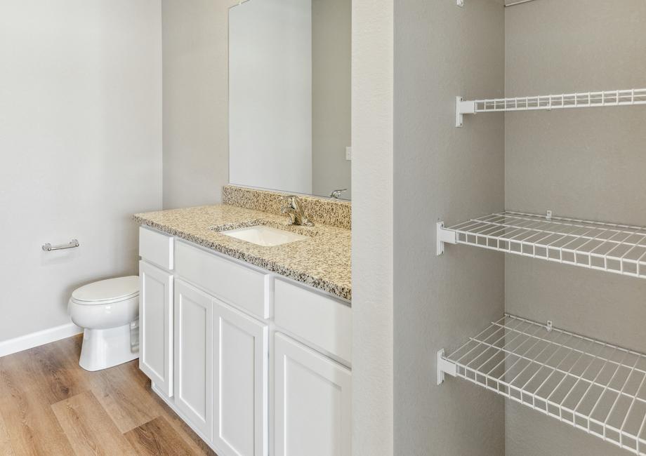 Master bathroom with storage shelves and white cabinets.