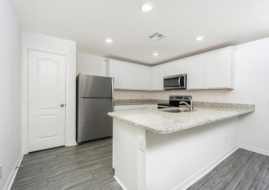 Chef-read kitchen with white cabinets and granite countertops