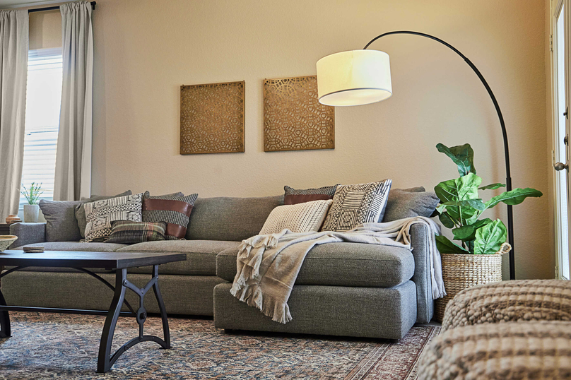Staged living room with a gray couch and standing lamp.