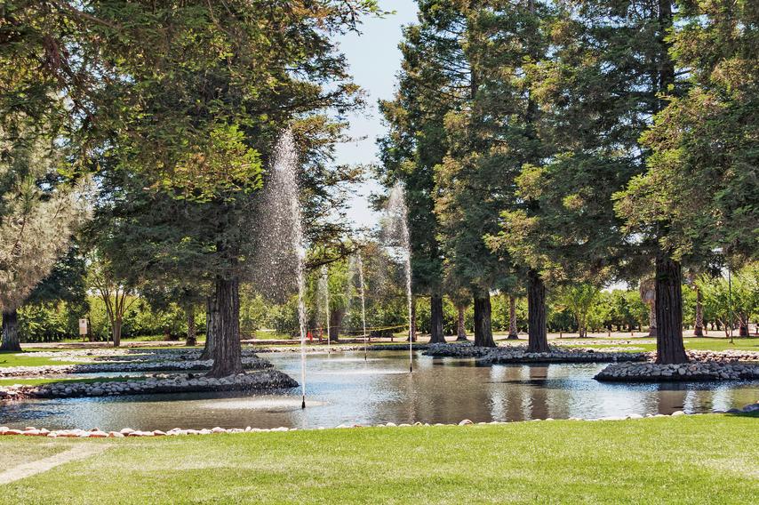 Park in Modesto, California is off of Yosemite Blvd. with picnic area and tables along with lawn, landscaping and beautiful fountains in the small lake.