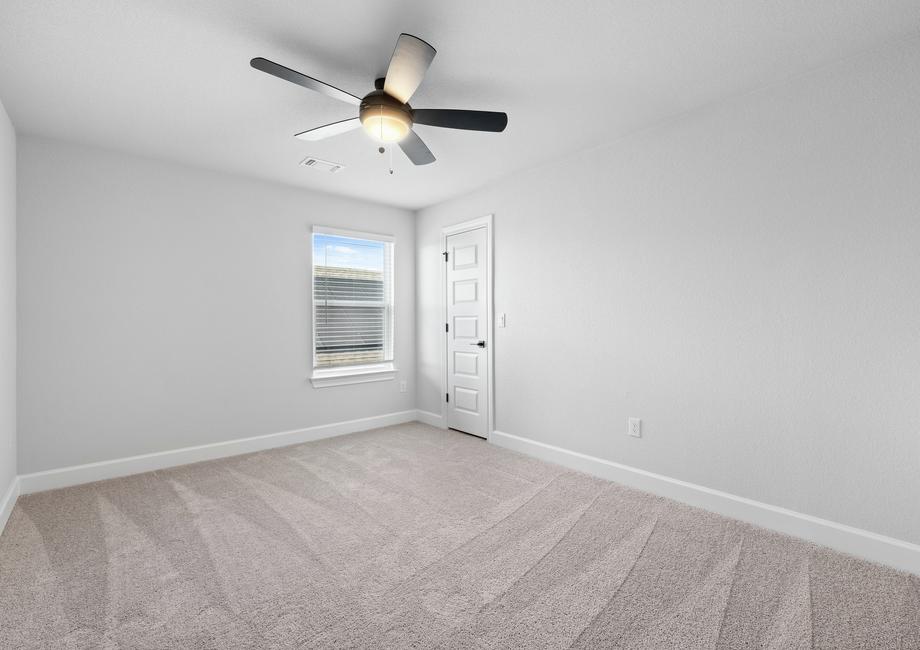 Spacious secondary room including carpet and ceiling fan.