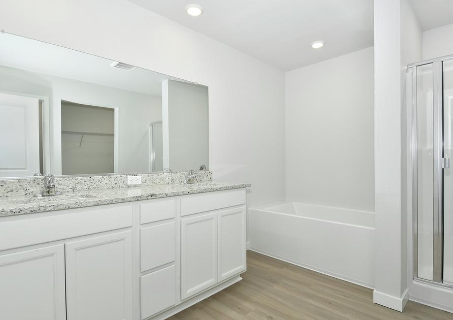 The master bathroom has a dual sink vanity and a soaking tub and step in shower.