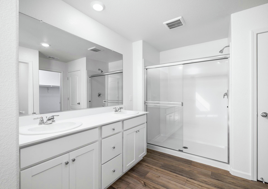 The master bathroom has a step in shower and large dual sink vanity.