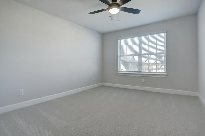 Secondary bedroom with large windows and a ceiling fan.