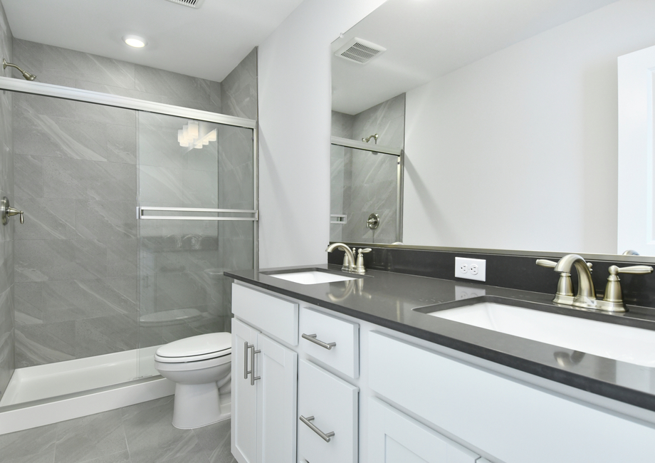 The master bathroom has a dual sink vanity and a step in shower. 