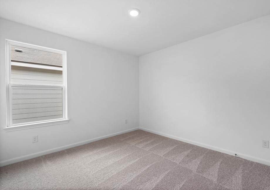 Secondary bedroom with a single window and tan carpet.