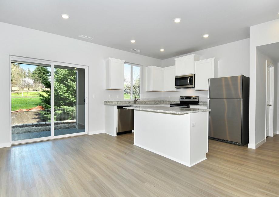 The kitchen has white cabinets and stainless steel appliances and has room for a dining table.