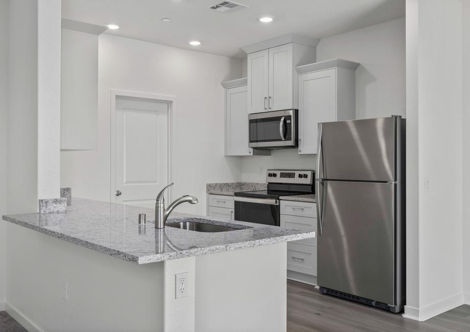 The kitchen has stainless steel appliances and plank flooring.