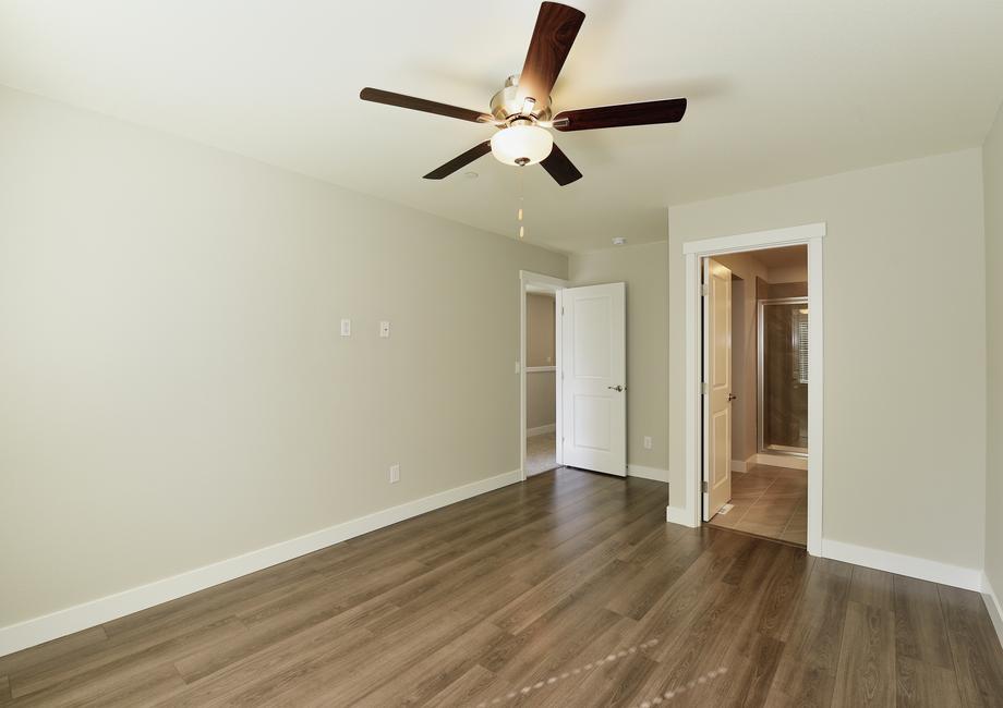 The master bedroom has plank flooring and a ceiling fan.