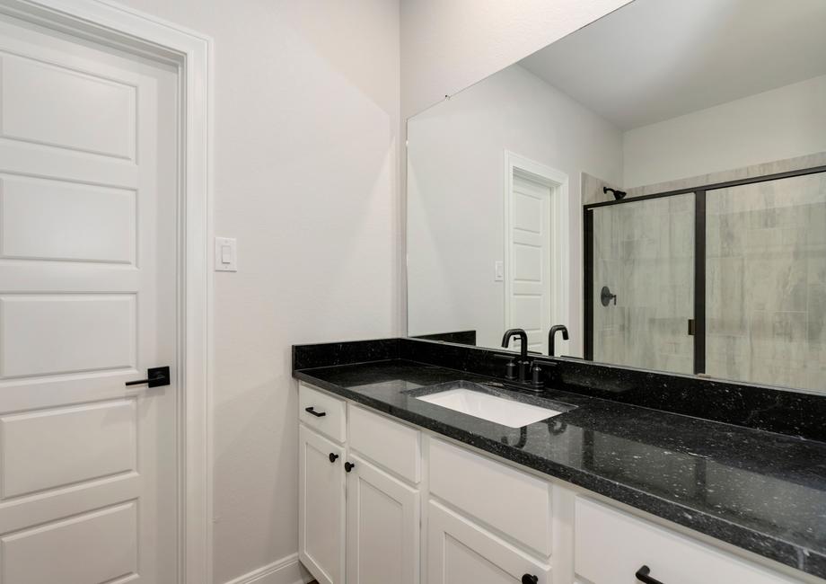 Master bathroom with black countertops and an attached walk-in closet.