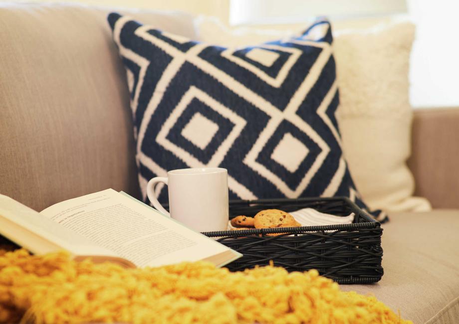 Home with light color couch, black and white patterned pillow and an open book.